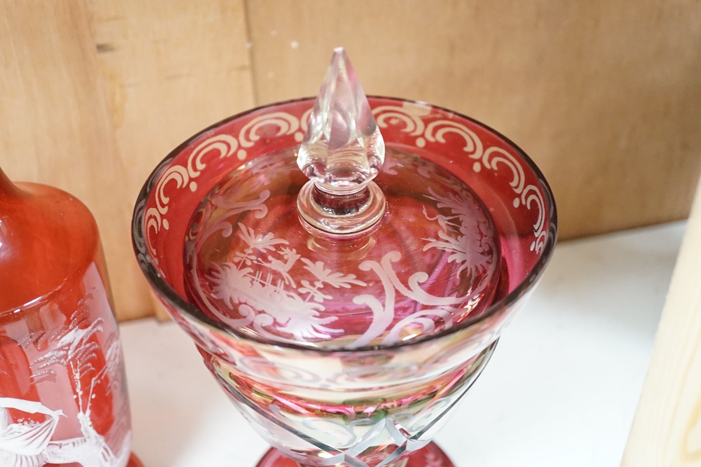 A collection of cranberry glass, a dump paperweight, another and a sweetmeat jar, tallest 28.5 cm